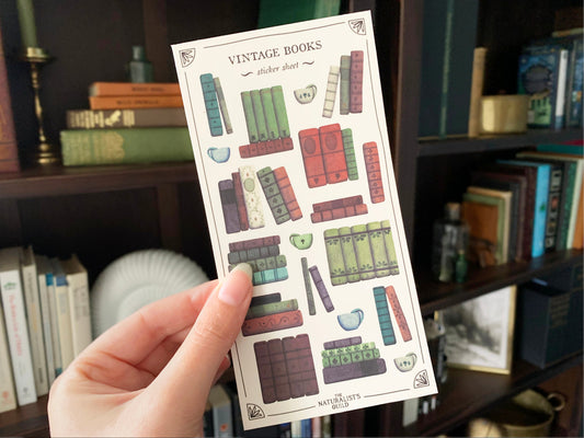 Sticker sheet of a vintage books and cups of tea to be used in planner or journal, held in front of a dark academia style bookshelf. The Naturalist's Guild.